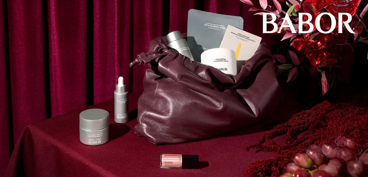 Productos Babor en un bolso de cuero color burdeos: un tarro de crema, suero, bálsamo limpiador, mascarilla y un brillo labial, todos sobre un mantel a juego.
