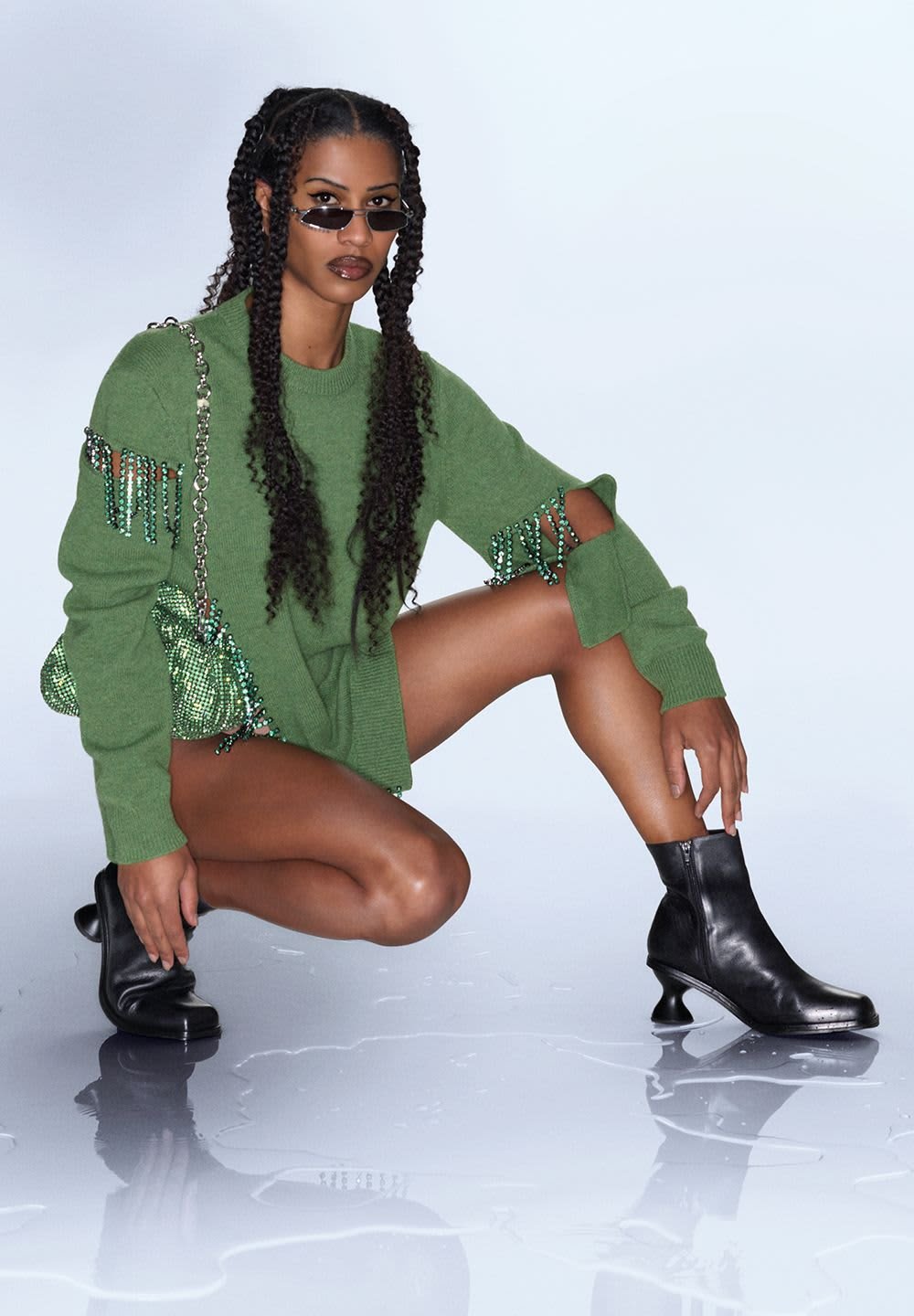 Green knitted jumper with fringed beaded detail, black ankle boots with a distinctive heel, and a sparkling green beaded handbag.