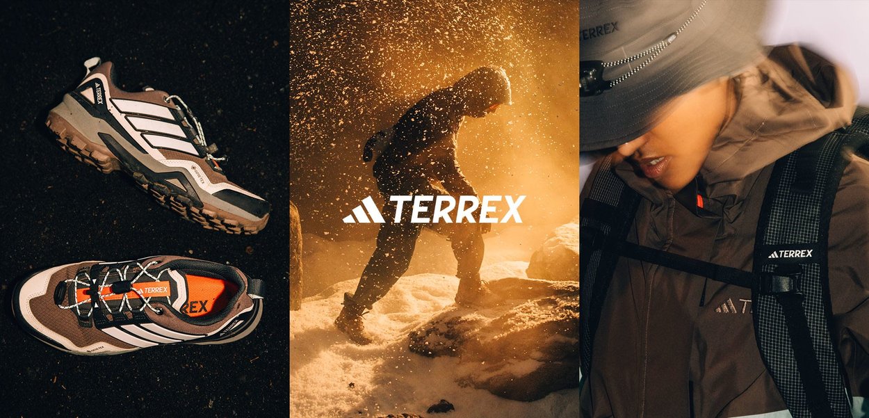 Giacca impermeabile marrone con cappuccio, indossata sopra uno zaino in rete nera con il logo "TERREX" ben visibile. Il volto della persona è parzialmente oscurato.
