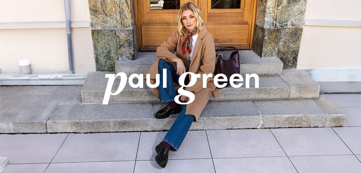 Brauner Mantel, blaue Jeans, schwarze Schuhe und gemusterter Schal. Eine lila Handtasche liegt auf grauen Steinstufen vor einem Holzportal.