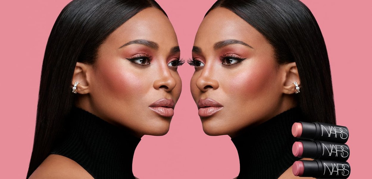 Due profili identici con capelli neri lucidi, indossando dolcevita neri, che mostrano trucco e tre tubetti di rossetto NARS in diverse tonalità di rosa.