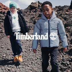 Dva chlapci v zimních bundách kráčejí po kamenitém terénu s vulkanickými kameny pod částečně oblačnou oblohou.