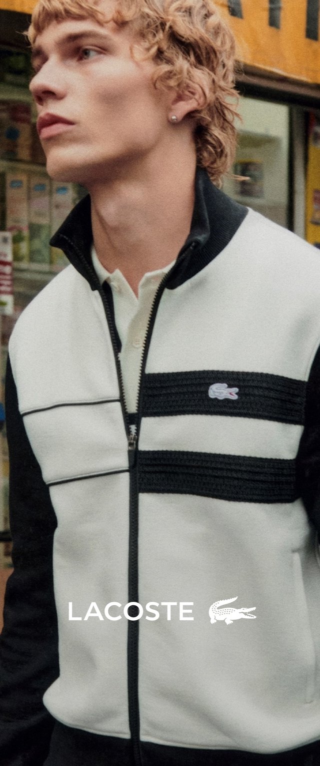 Veste zippée blanche et noire avec un design rayé, texture douce et logo Lacoste sur la poitrine gauche. Col polo classique.