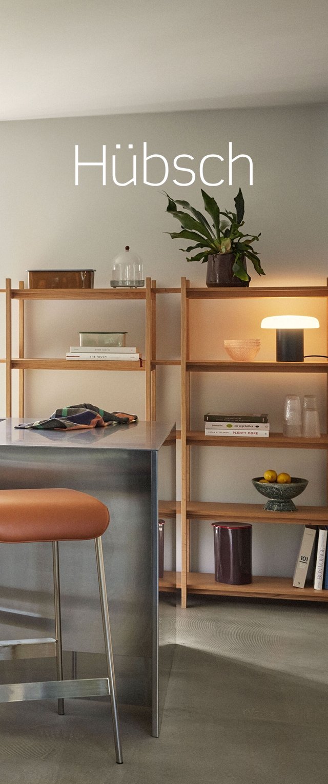 Dřevěné regály s různými dekorativními předměty, kovový ostrov s oranžovým sedadlem a jemné osvětlení vytvářejí funkční interiérový prostor.