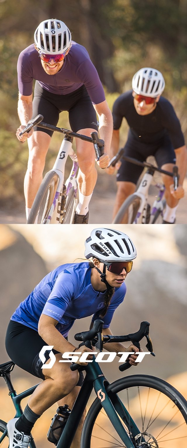 Zwei Radfahrer in Sportbekleidung fahren auf einem Pfad. Der erste trägt ein lila Oberteil und einen weißen Helm; der zweite hat ein blaues Oberteil und einen schwarzen Helm.