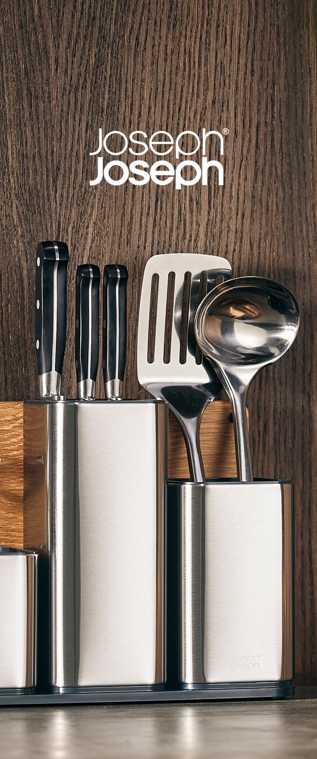 Edelstahl-Besteckhalter mit Messern mit schwarzem Griff, einem Pfannenwender und einem Löffel, in einem eleganten, modernen Design vor Holz angeordnet.