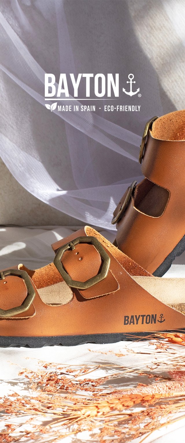Brown leather sandals with hexagonal brass buckles, cork insole, and black rubber sole. Branding visible on the side. Eco-friendly design.