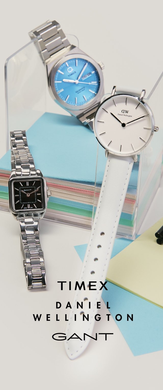 Tre orologi da polso di Timex, Daniel Wellington e Gant esposti su supporti trasparenti e fogli di carta colorati impilati.