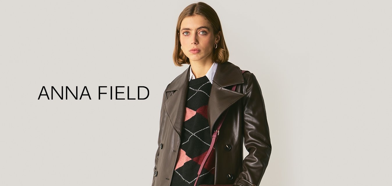 Hnědý kožený trenčkot s širokým límcem a dvouřadým zapínáním, který je kombinován se vzorovaným černým svetrem a vínovou taškou s krokodýlí texturou.