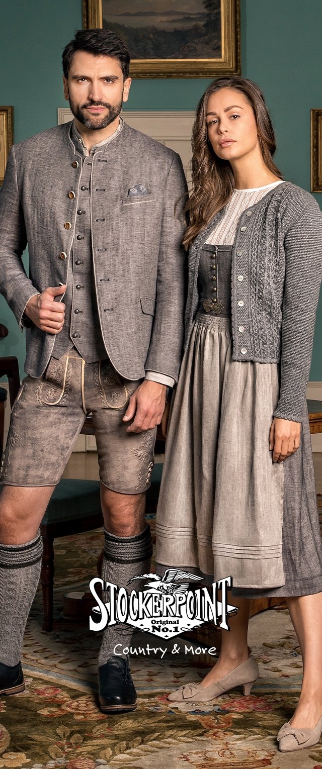 Traditionelle Kleidung aus grauem Leinenstoff. Mann in einer kurzen Jacke und knie-langen Shorts. Frau in einem Dirndl mit einer strukturierten Strickjacke.