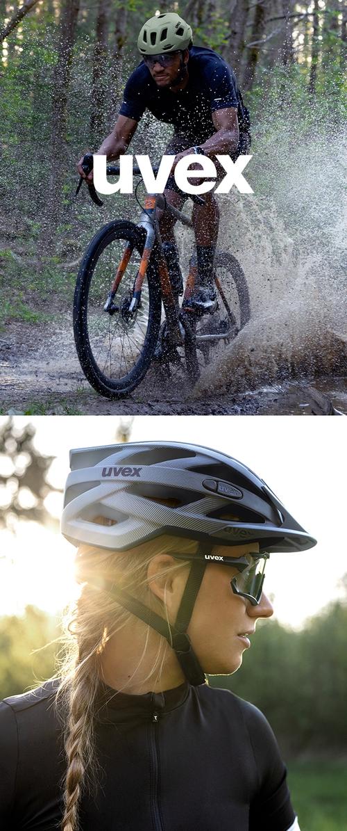 Uvex fietshelm, groen, met ventilatiesleuven; model in zwarte fietskleding en zonnebril; zonovergoten achtergrond met zachte focus.