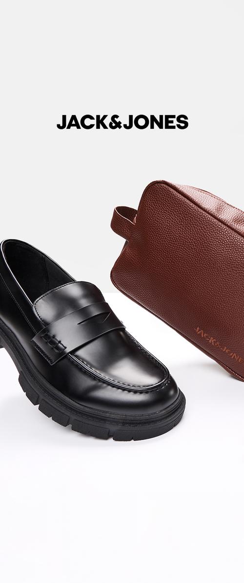 Mocasines de cuero negro con suela gruesa al lado de una bolsa de cuero marrón texturizado embosada con el logo de Jack & Jones sobre un fondo blanco.