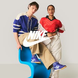 Dva mladí dospělí v neformálním oblečení pózují; jeden sedí na modré moderní židli, druhý stojí s rukou v kapse před jednoduchým pozadím.