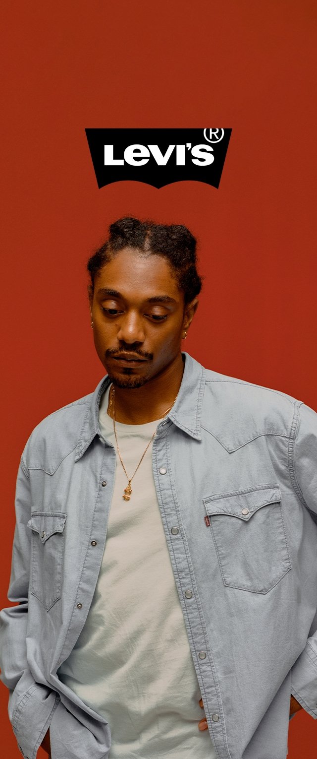 Light blue denim shirt with two chest pockets, layered over a light green t-shirt, against a solid red background, features Levi's logo above.