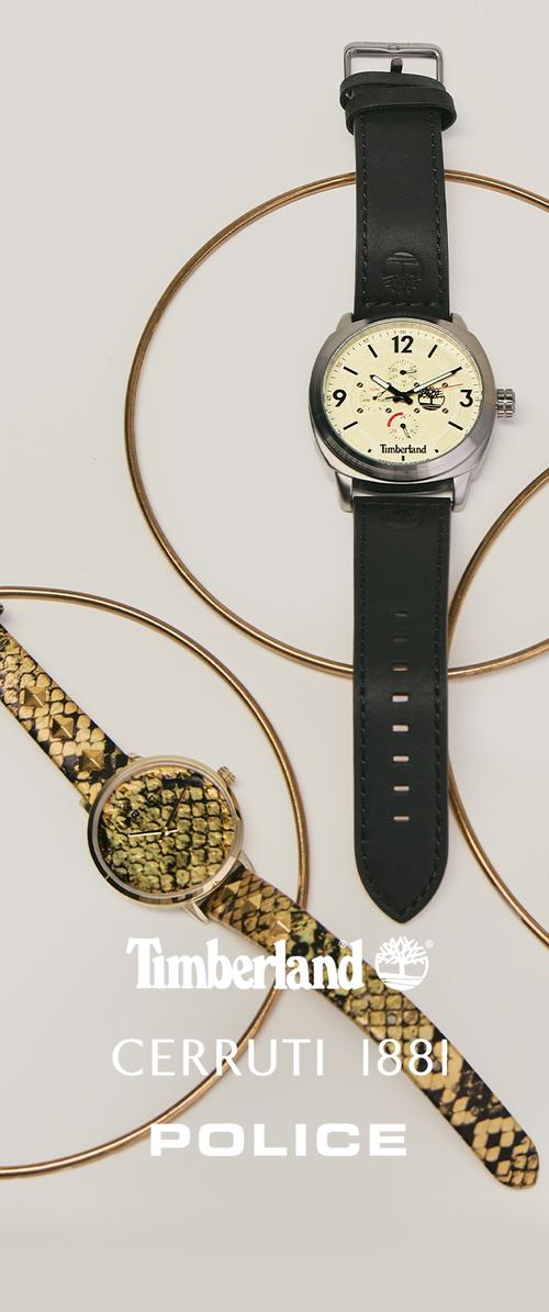 Dos relojes de pulsera con detalles circulares dorados: uno con correa de cuero negro y esfera blanca, y el otro con correa de piel de serpiente dorada y esfera a juego.