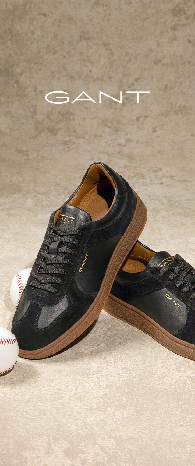 Zapatillas negras hechas de ante y cuero con suelas de goma marrón. Presentan cordones redondos, un cuello acolchado y un branding sutil.