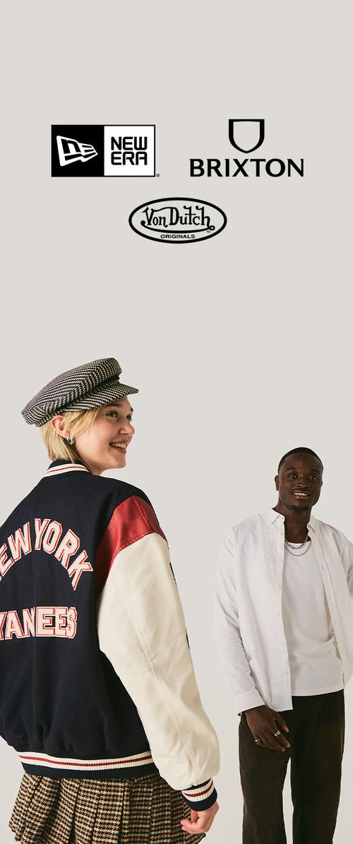Divi smaidīgi modeļi, viens valkā New York Yankees jaku un cepuri, otrs baltu kreklu, virsū New Era, Brixton un Von Dutch logotipi.