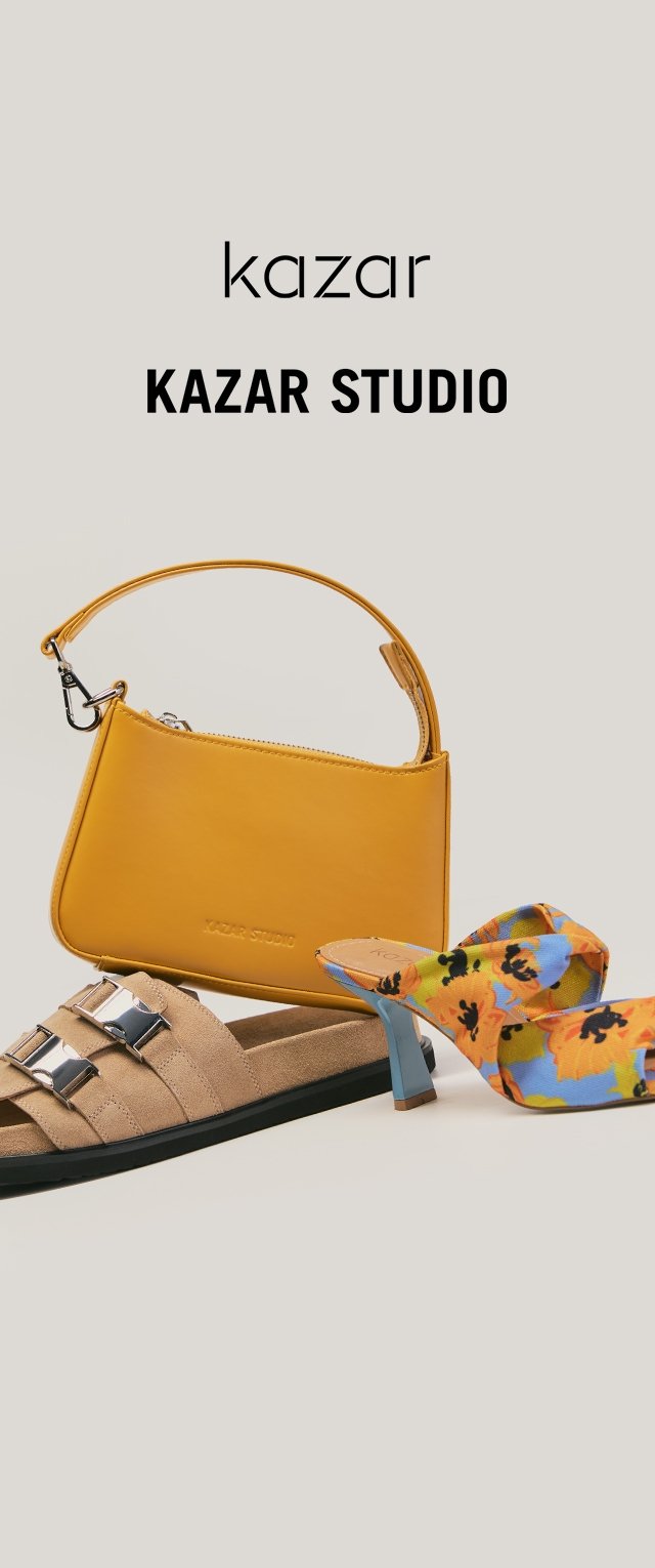 Dzeltena soma ar īsu rokturi, bēša zamša slidkalni, kas ir aprīkoti ar metāla sprādzēm, un zili ziedu raksta augstpapēžu mule apavi.