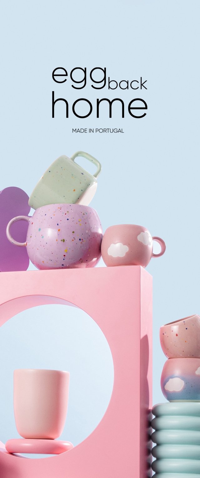 Kleurrijke keramische mokken en kopjes in roze, groen en paars met gespikkelde patronen, gerangschikt op een roze geometrische display tegen een lichtblauwe achtergrond.