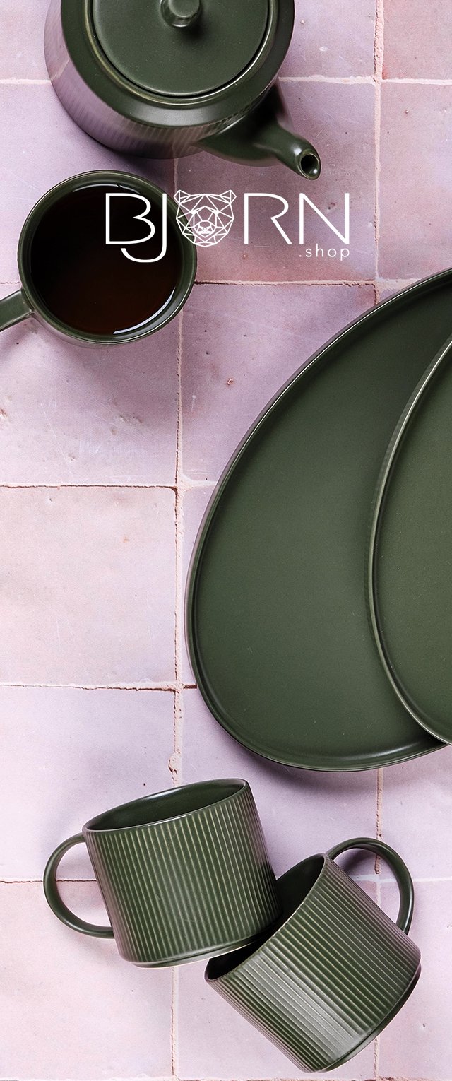Teiera in ceramica verde, tazze e vassoio; texture rigata sulle tazze, superficie liscia sulla teiera e sul vassoio, disposti su uno sfondo di piastrelle rosa chiaro.