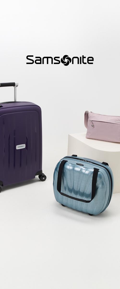 Three Samsonite travel bags: a purple hard-shell suitcase, a blue soft-sided duffel with black accents, and a light pink clutch with a zipper.