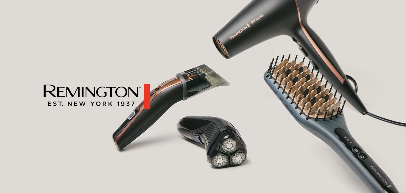 Černý a měděný fén na vlasy, elektrická žehlička na vlasy, zastřihovač vousů a elektrický holicí strojek se třemi hlavami na světlém pozadí.