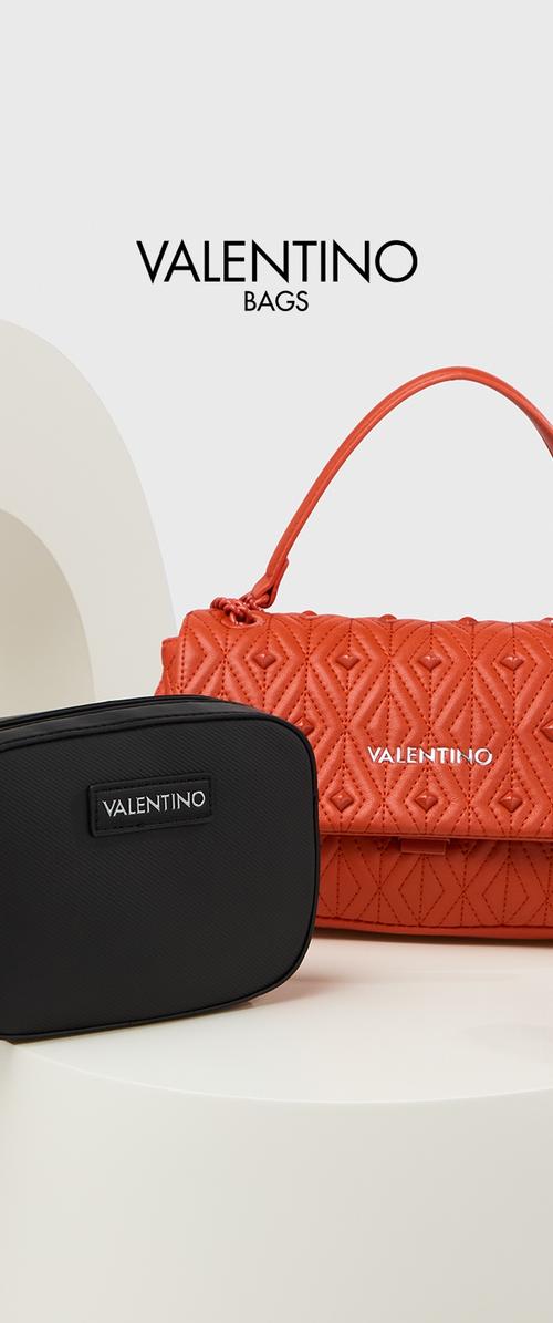Bolso de mano de cuero acolchado naranja con un asa corta, junto a un bolso rectangular negro texturizado con un parche de logo. Ambos etiquetados como "Valentino."