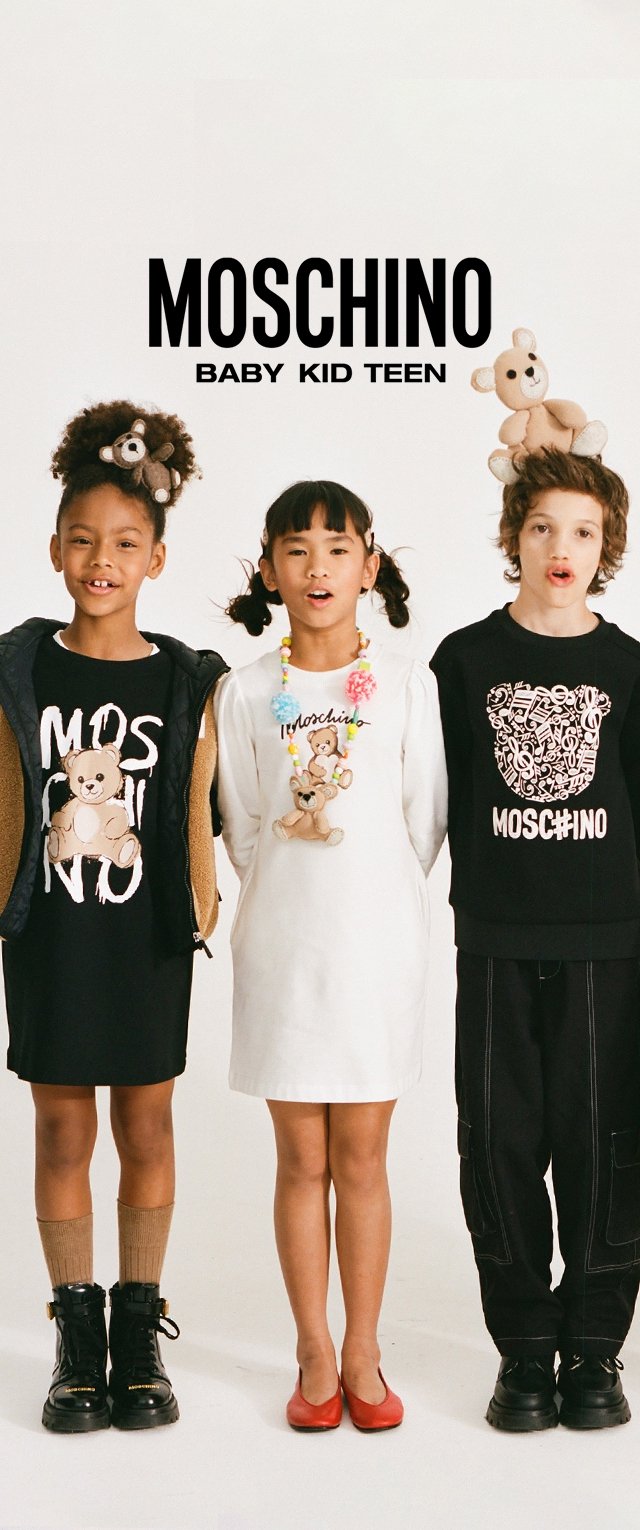 Tres niños posan vistiendo ropa de Moschino con diseños de ositos de peluche; dos llevan ositos en la cabeza y uno lleva un collar de cuentas coloridas.