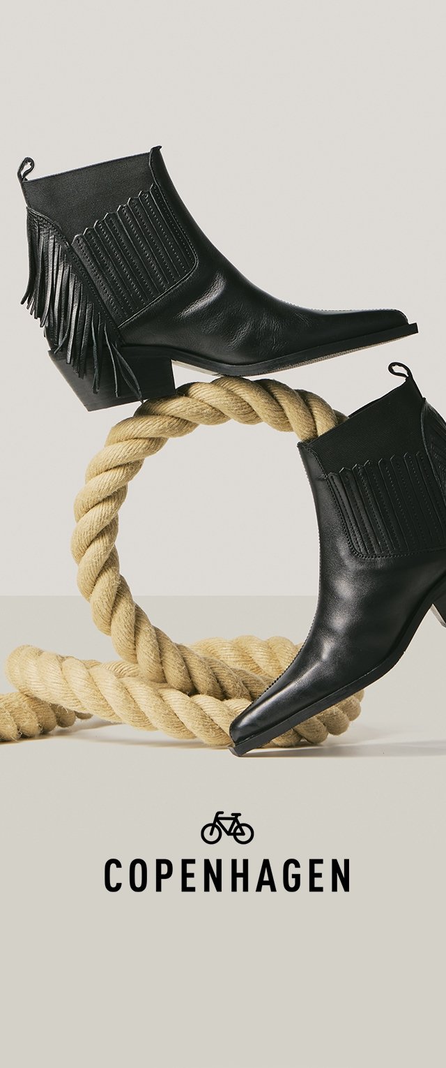 Dos botines negros de cuero con flecos y laterales elásticos, exhibidos sobre una cuerda beige retorcida, con la palabra "Copenhagen" y un ícono de bicicleta debajo.