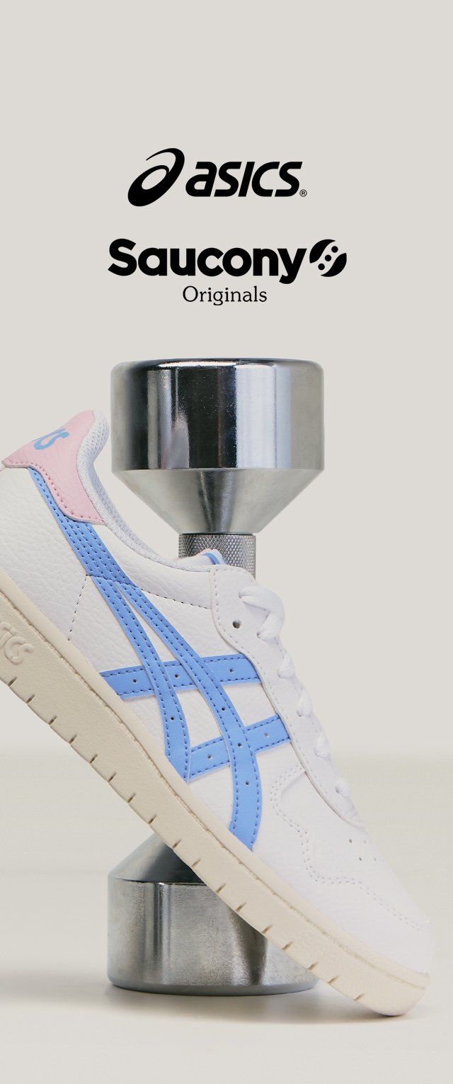 Witte sneaker met blauwe strepen en roze hiel detail rustend op een zilveren dumbbell, met Asics en Saucony Originals-logo's erboven.
