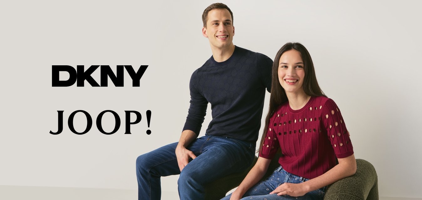 Mladý muž v černém svetru a džínách a žena v červeném topu a ozdobených džínách sedící na moderní texturované židli u bílé zdi.