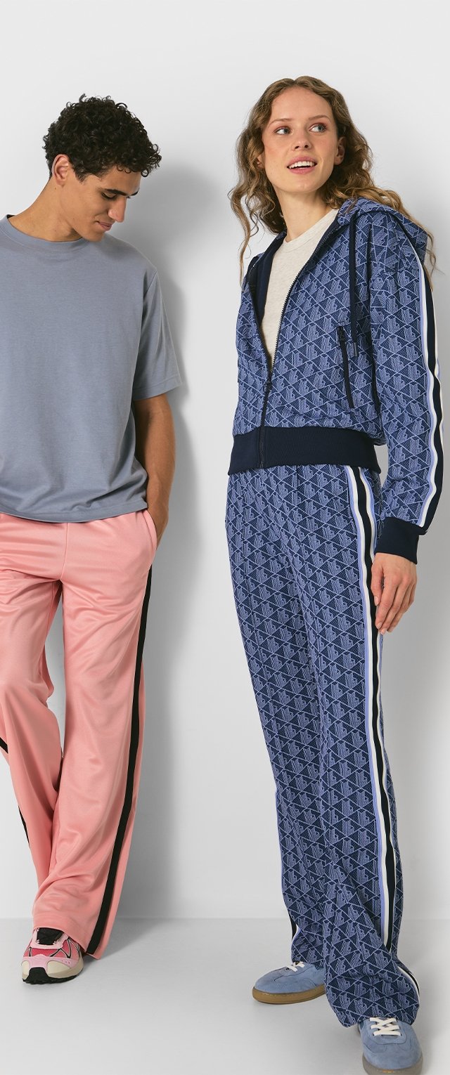 Conjunto de jogging en azul marino con un patrón geométrico, que incluye una chaqueta con cremallera y pantalones a juego con rayas blancas en los laterales. Pantalones rosa claros con rayas negras.