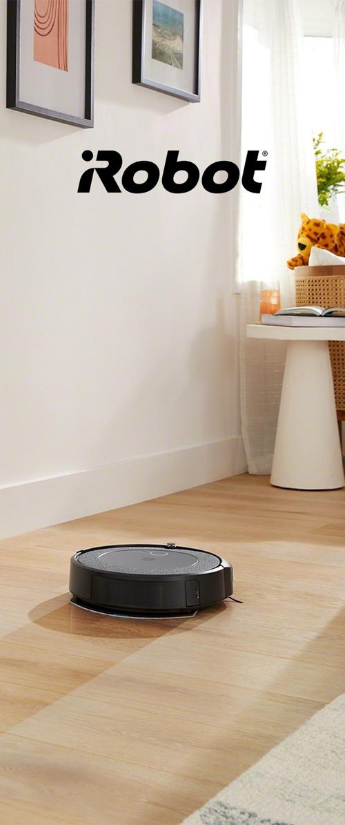 Aspirateur robot rond noir sur un sol en bois clair, avec une surface supérieure texturée et une petite brosse latérale pour nettoyer les bords.
