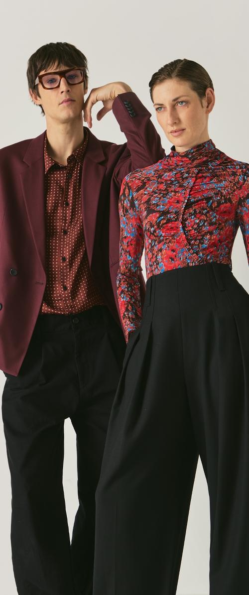 Blazer burdeos, camisa de lunares y pantalones negros de cintura alta en un modelo; top de flores en otro. Ambos conjuntos presentan patrones distintos.