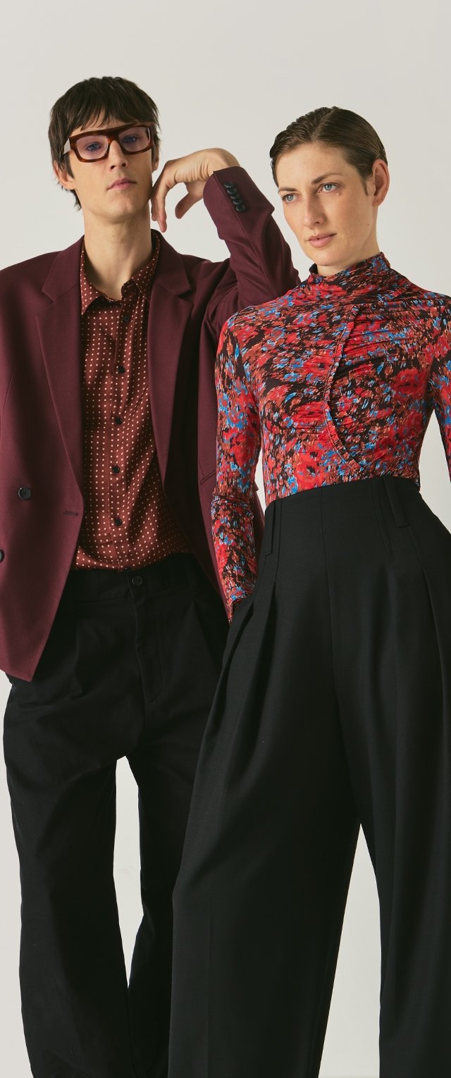 Bordowy żakiet, koszula w kropki i czarne spodnie z wysokim stanem na jednym modelu; na drugim modelu kwiatowy top. Oba zestawy mają wyraźnie różne wzory.