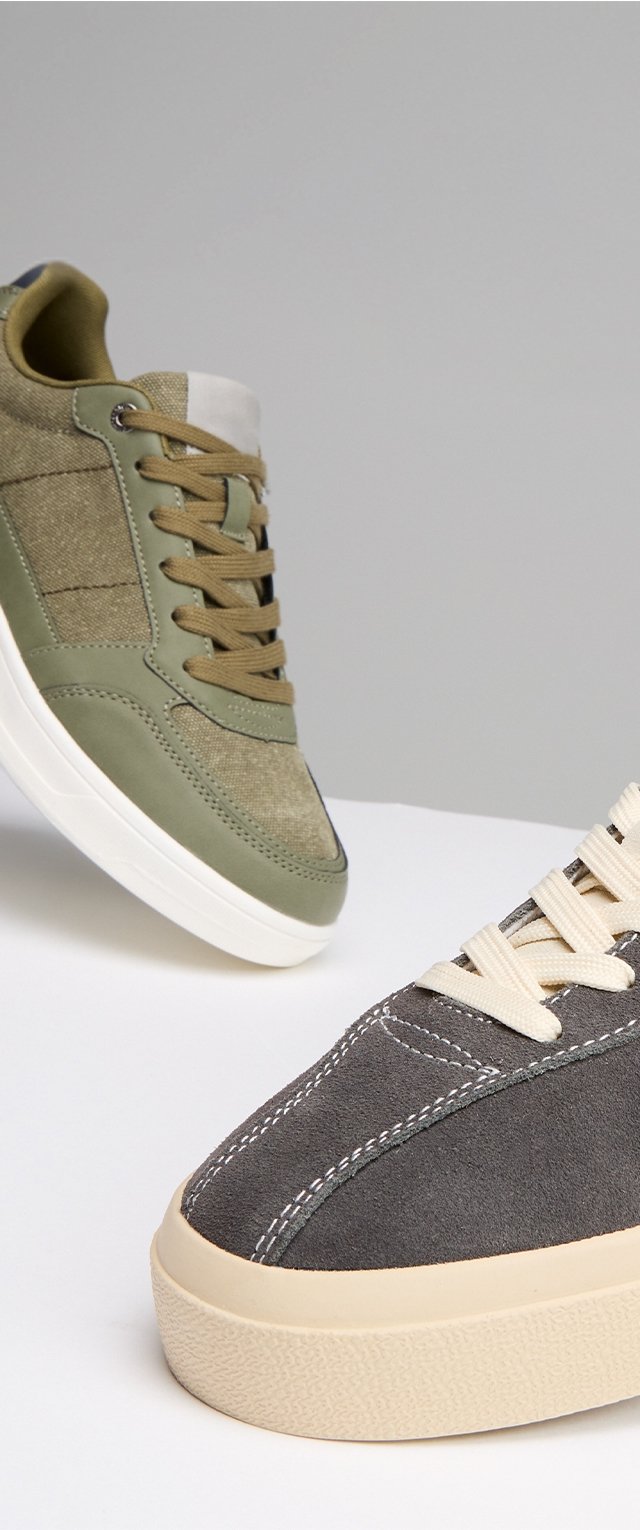 Sneakers in tela con tomaia in suede verde oliva e grigio scuro, lacci piatti, suole intermedie bianche a contrasto e dettagli di cucitura sottili.