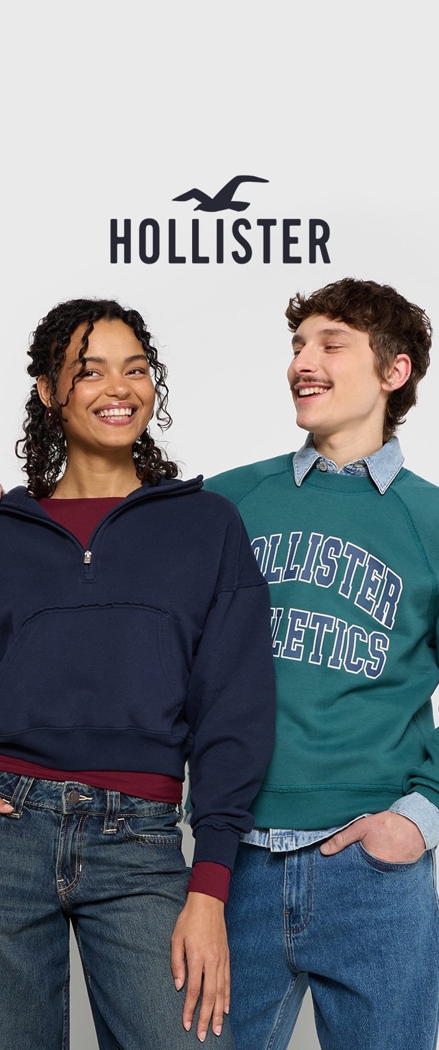 Dwa modele w casualowych ubraniach: granatowy sweter na zamek na burgundowej koszulce oraz zielony sweter z okrągłym dekoltem z napisem "HOLLISTER ATHLETICS" na białym tle. Obaj mają na sobie dżinsy.