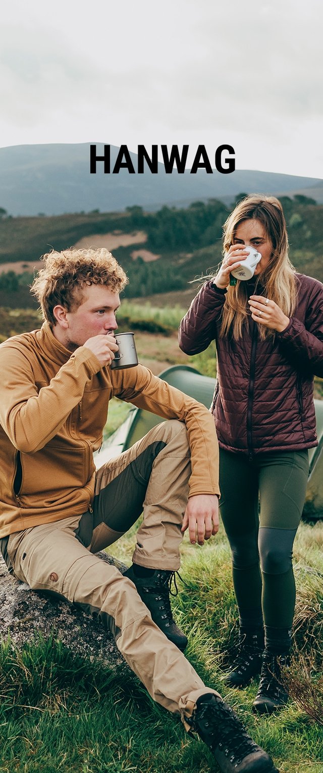 Due persone all'aperto bevono da delle tazze. Una indossa una giacca zip marrone e pantaloni beige, l'altra un giubbotto imbottito rosso scuro e leggings verdi.