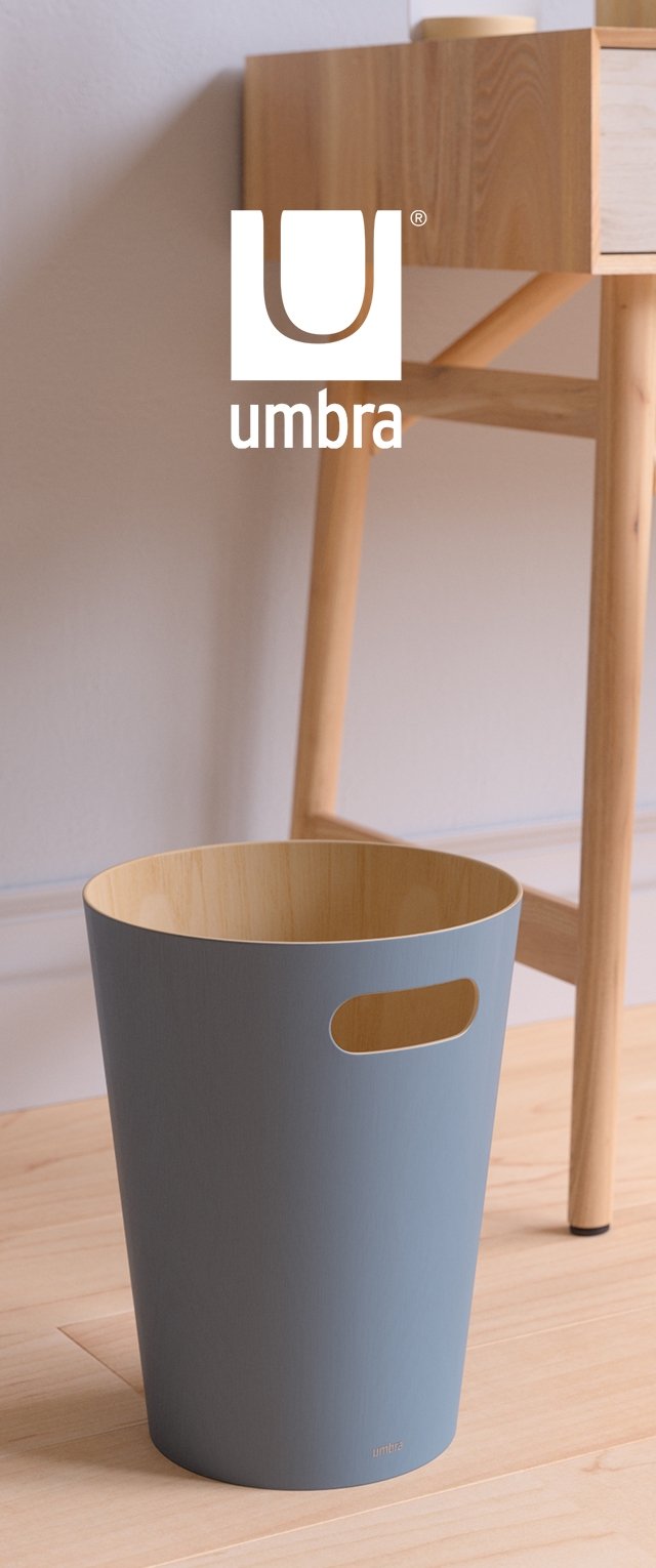 Okrągły kosz na śmieci w jasnoniebieskim kolorze z wnętrzem z bambusa i wyciętymi uchwytami, umieszczony obok drewnianego stołu na jasnej drewnianej podłodze.