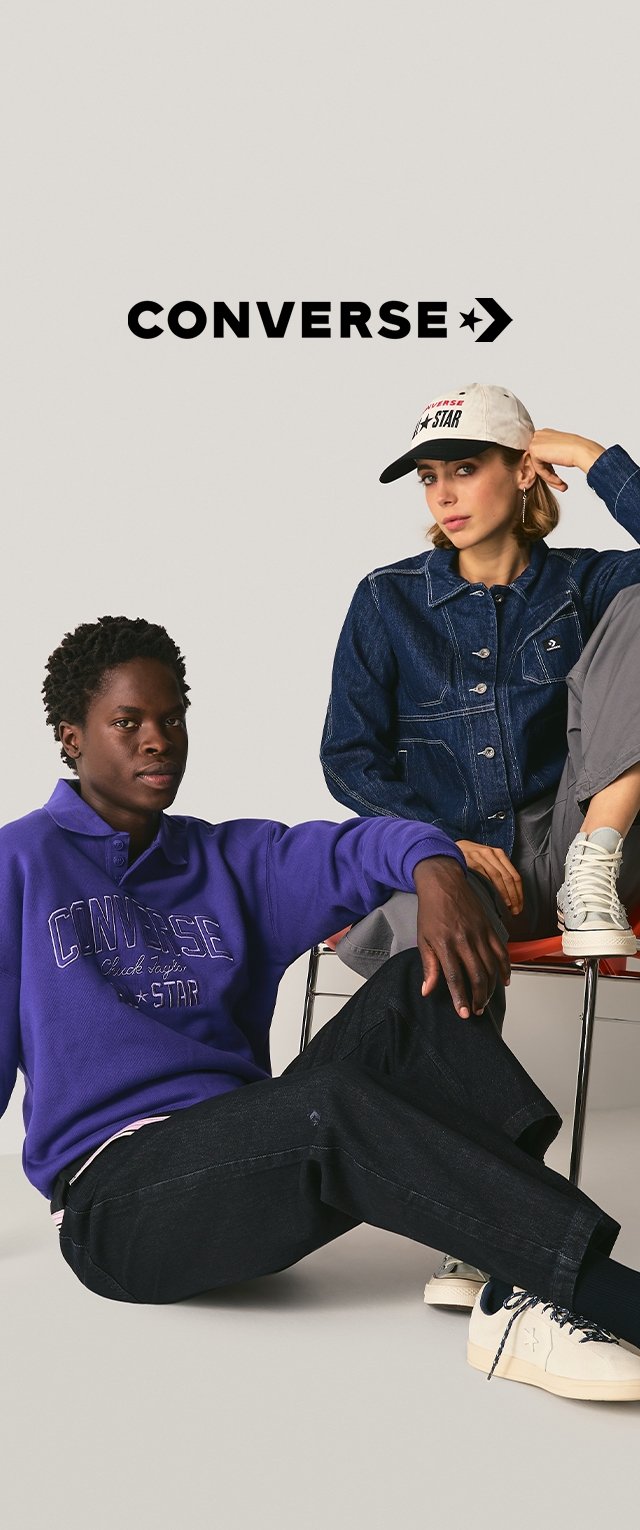 Fioletowa bluza z białym logo, ciemne dżinsy i białe trampki. Dżinsowa kurtka i czapka baseballowa noszone przez modele. Proste tło.