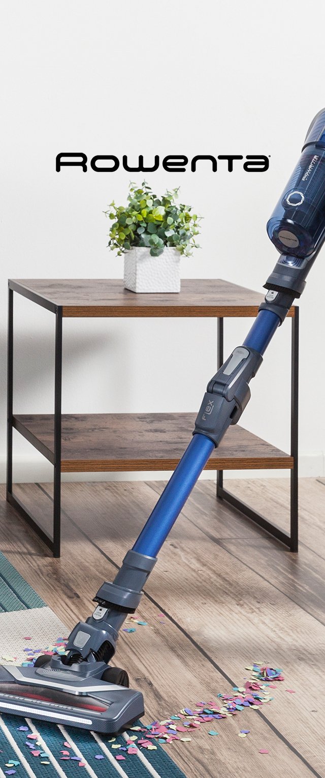 Akku-Staubsauger mit blauen Gehäuse und grauen Akzenten, flexiblem Griff und einem flachen Reinigungskopf auf einem Holzboden mit verstreutem Konfetti.