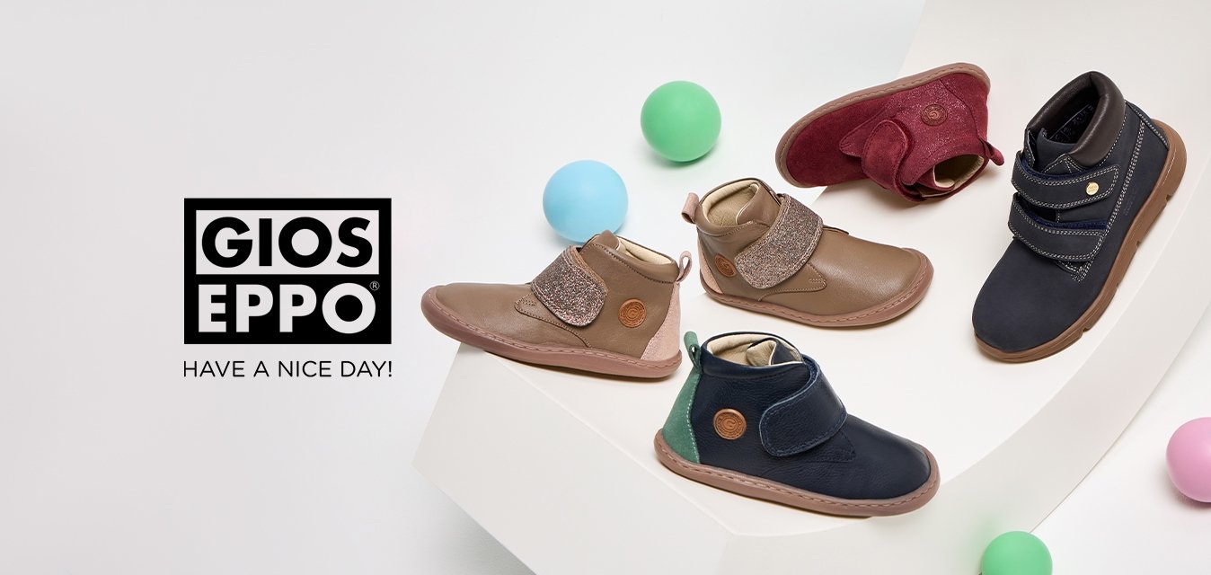 Čtyři páry dětských bot: hnědé kožené s třpytivým páskem, burgunské semišové, námořnicky modré na suchý zip a námořnicky modré kožené s zeleným akcentem na bílém podkladu.