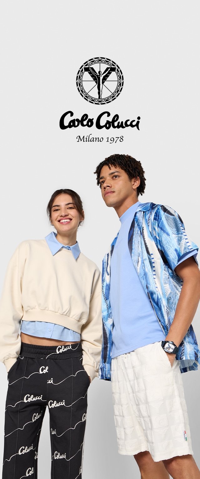 Dos modelos llevan atuendos casuales. Uno viste un sudadera oversized blanca con una camisa azul debajo y pantalones negros con estampado. El otro lleva una camisa azul y pantalones cortos con estampado.