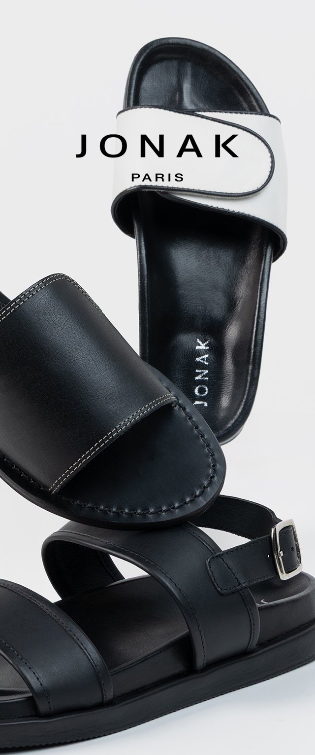 Sandalias de cuero negro con una correa de hebilla y diseño de bandas cruzadas; sandalia deslizante de color blanco y negro con acabado suave y logotipo.