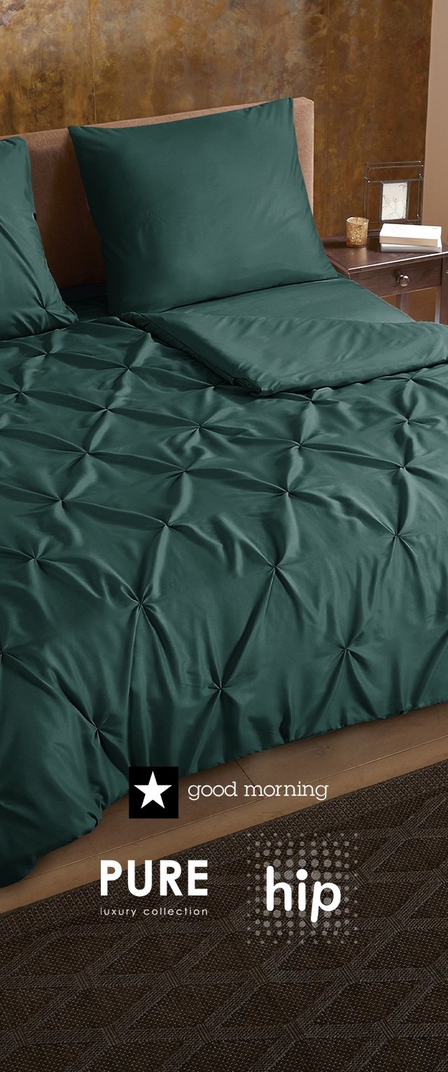 Donkergroen decoratief beddengoed met een getextureerd, getuft ontwerp. Inclusief twee vierkante kussens op een licht houten bedframe naast een nachtkastje.