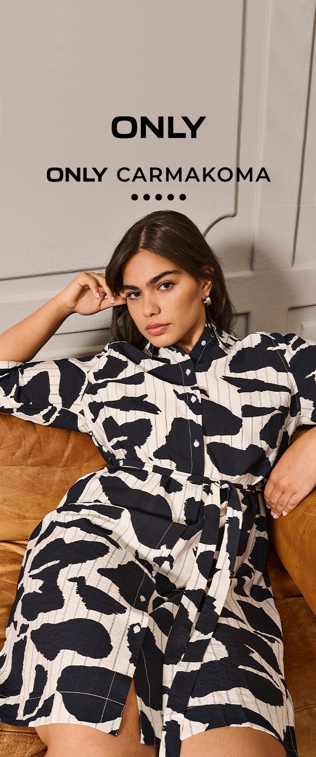 Vestido camisa color crema con patrones abstractos negros, con cuello con solapa, botones y cintura con cinturón, mostrado en un sofá marrón.