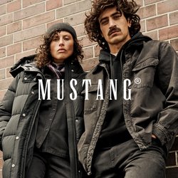 Dvě osoby v tmavém neformálním zimním oblečení a botách opírající se o cihlovou zeď, jedna má čepici a péřovou bundu.