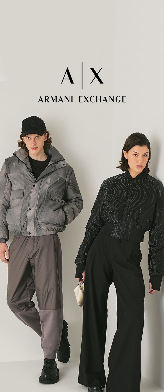 Twee modellen zijn gekleed in bovenkleding: een grijze pufferjack en een zwarte, gestructureerde bomberjack, gecombineerd met losse broeken en zwarte laarzen.