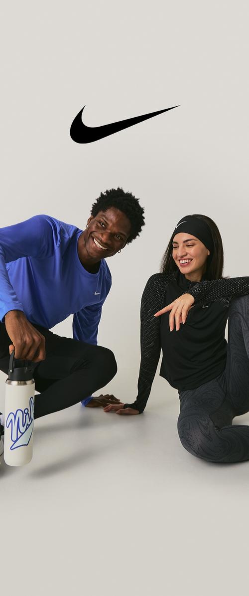 Vêtements Nike comprenant un haut bleu à manches longues, un haut noir à manches longues avec des accents texturés, et une bouteille d'eau blanche avec un logo bleu.