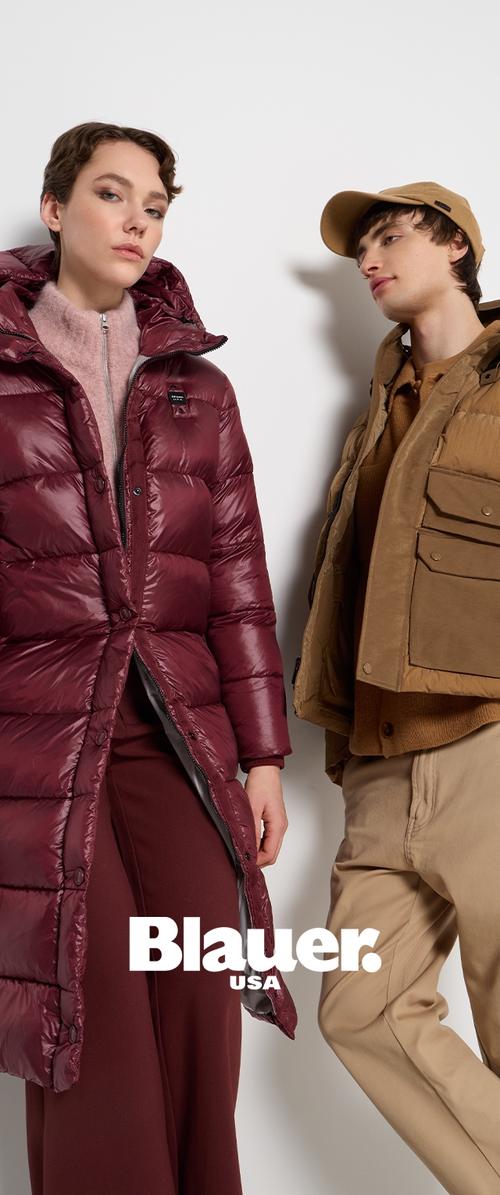 Langer bordeauxfarbener Puffer-Mantel mit Reißverschluss und großen gesteppten Abschnitten, kombiniert mit einer hellbraunen Jacke mit Knopfleiste, die mehrere Taschen hat.